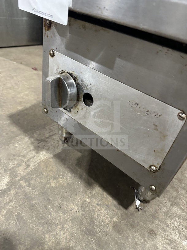 Commercial stainless steel gas-powered countertop flat top griddle on legs, visible control knob, used condition with some rust.
