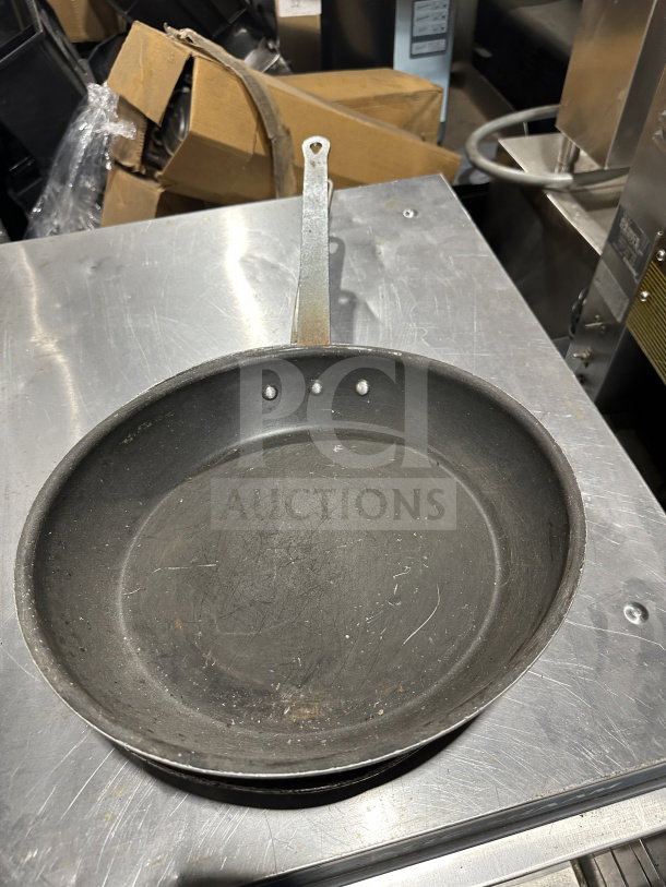 Commercial stainless steel non-stick fry/griddle pan with riveted handle, showing signs of use; ideal for high-volume cooking.