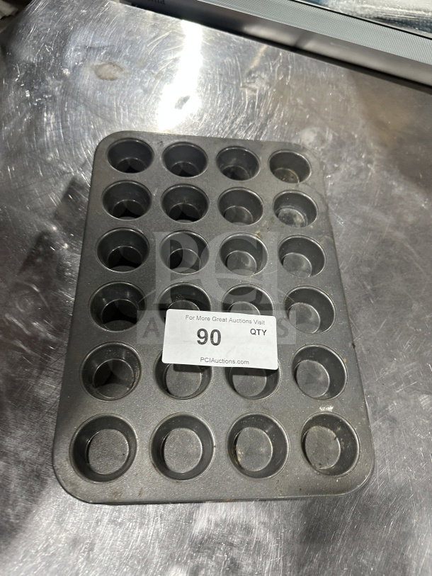 Commercial 24-cup non-stick mini muffin pan on metal surface with auction label. In good condition.