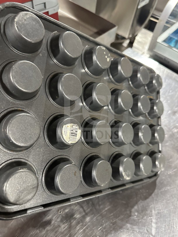 Commercial 24-cup non-stick mini muffin pan, used condition, with visible barcode sticker on bottom.