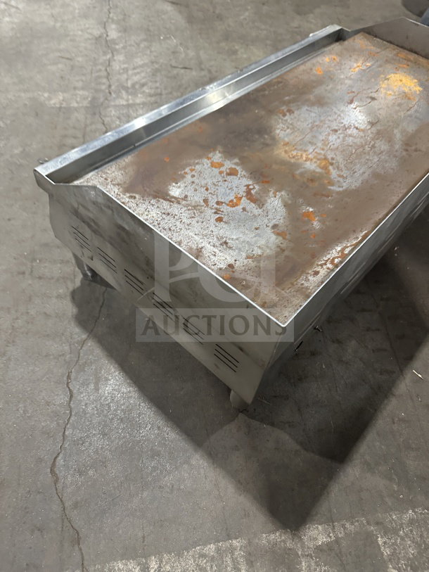 Avantco 36" stainless steel flat griddle, model 177EG36N, with thermostatic controls, back and side splash, on legs.