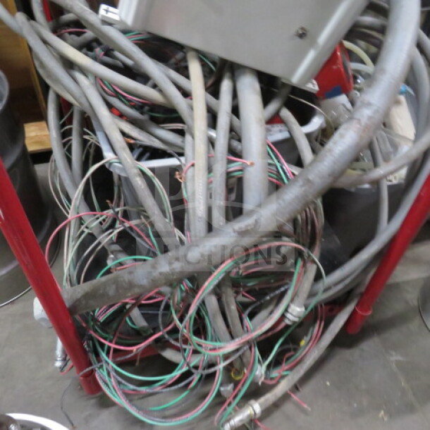A tangled mass of cables and hoses on a metal frame, part of a 253-gallon, three-vessel brew house with a heat exchanger.