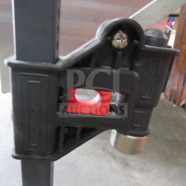 Heavy-duty black and red bottle capper in good condition, featuring a sturdy metal base and secure handle mechanism.