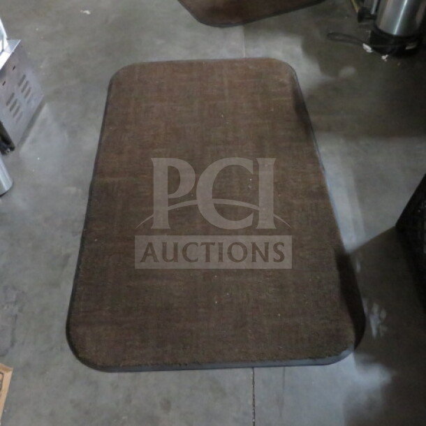 Brown rectangular rug, 36x60 inches, with rounded edges. Used condition, subtle woven pattern.