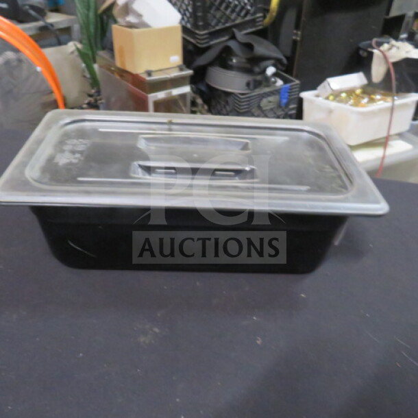 1/3 size, 4-inch deep black food storage container with lid. Used condition. Ideal for kitchen organization. Model: 2XBID.