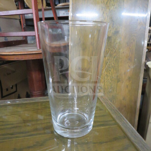 16oz clear beer glass, model 12XBID, pristine condition, cylindrical shape, on a wooden table.