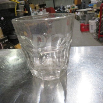 Clear rocks glass, model 12XBID, with a faceted design. Appears in used condition, on a metal surface.