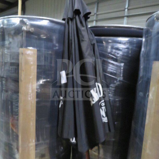 Jack Daniels patio umbrella, black with white branding, folded and in storage. Appears in good condition.