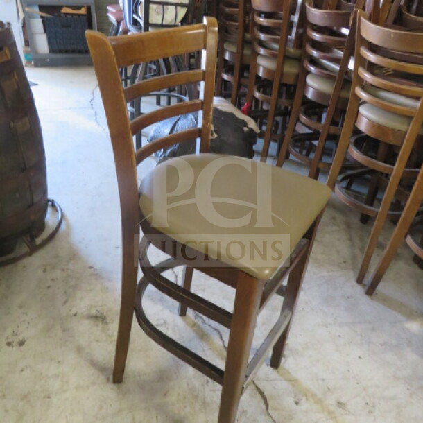 Wooden bar height chair with brown cushioned seat, ladder back design, and footrest. Used condition, sturdy structure.