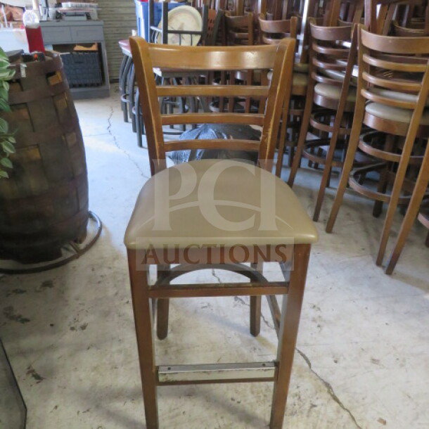 Wooden bar-height chair with brown cushioned seat, ladder-back design, in good condition. Model 4XBID.