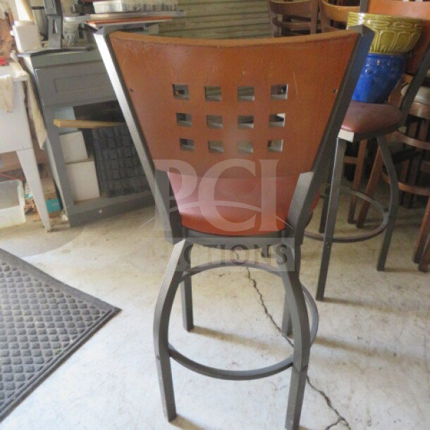 Metal bar height chair with cushioned swivel seat, featuring a lattice back design. Good condition. Model: 5XBID.