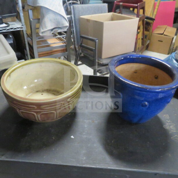 Two ceramic pots; one beige with an embossed geometric design, the other glossy blue. Both in used condition.