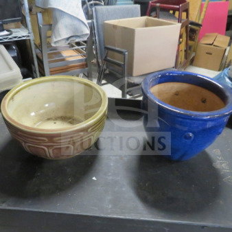 Two ceramic pots; one beige with an embossed geometric design, the other glossy blue. Both in used condition.