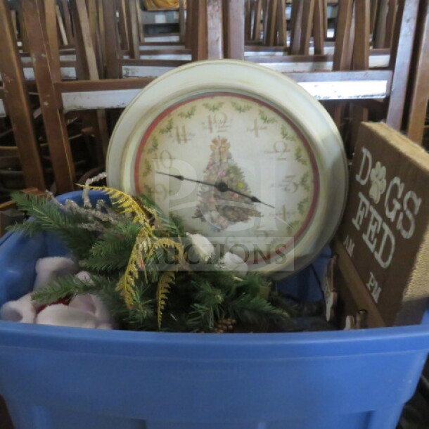 Mixed decor lot in blue bin, includes Christmas-themed clock, greenery, and "Dogs Fed" sign. Items appear gently used.