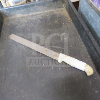 Vintage chef knife with long blade and white handle, appears used with some wear; no visible brand or model markings.