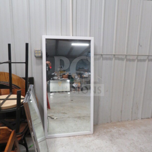 Wooden framed mirror, 30x60 inches, in good condition, placed against a metal wall.