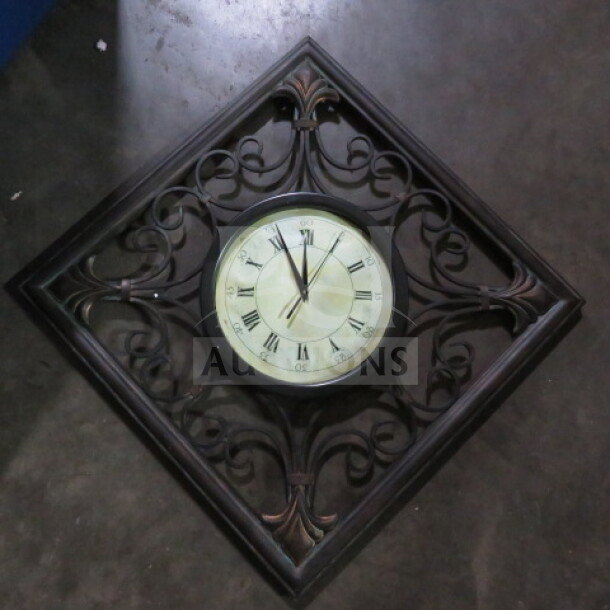 Decorative metal clock, 19.5x19.5 inches, ornate design, Roman numerals, vintage style, in good condition.