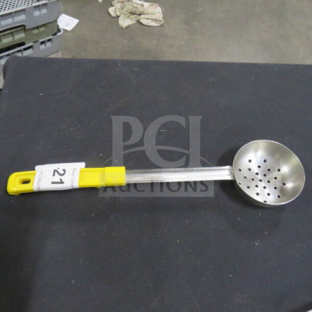 4oz perforated spoodle with stainless steel head and yellow handle, in good condition. Auction tag labeled "21."