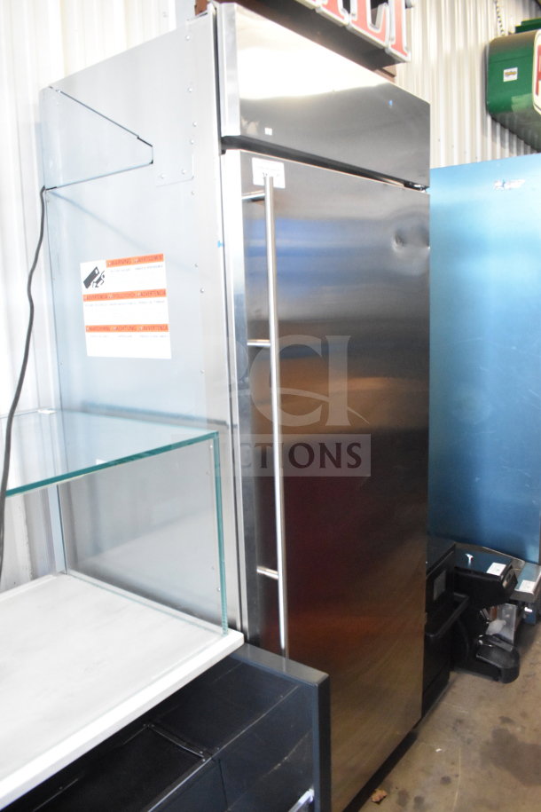 Stainless steel single door reach-in cooler with sleek design, sturdy handle, energy warning label, and good condition.