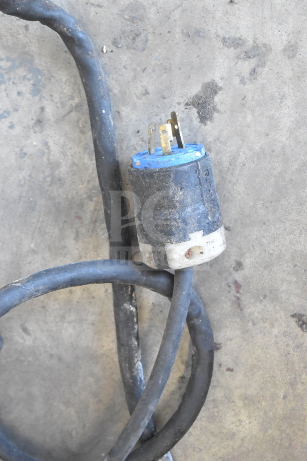 A dirty electrical cord with a blue and white plug on a concrete floor.
