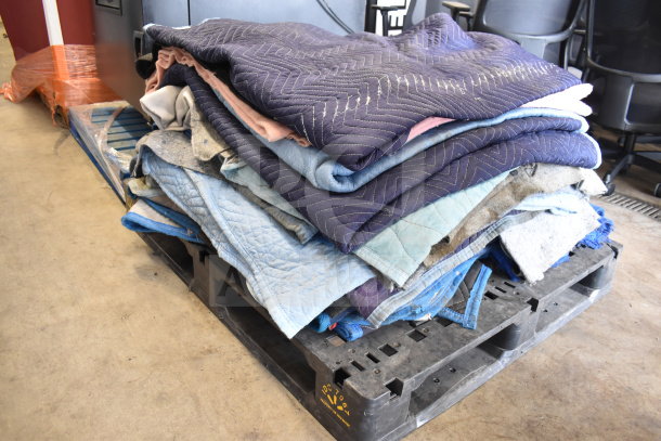15 moving blankets folded on a pallet, various colors, good condition, ideal for protecting items during transit.