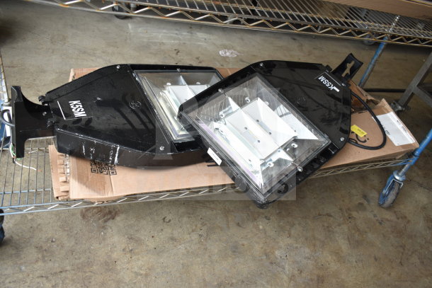 Four industrial K5SM light fixtures, black metal frame, slight wear, on a metal shelf. Includes wiring and a cardboard base.