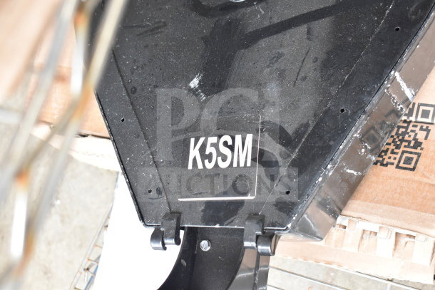 Black metal component labeled "K5SM" with visible scratches, part of a lot including lights and metal items.