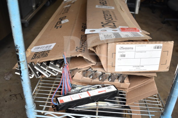 Cardboard boxes of i2Systems shelf light fixtures on a metal rack, including wiring. Boxes labeled with product details.