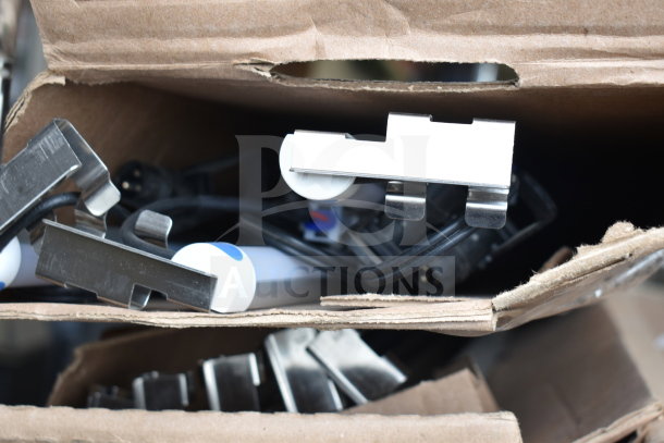 Cardboard box with assorted i2Systems light fixtures, featuring metal brackets and power cords, in good condition.
