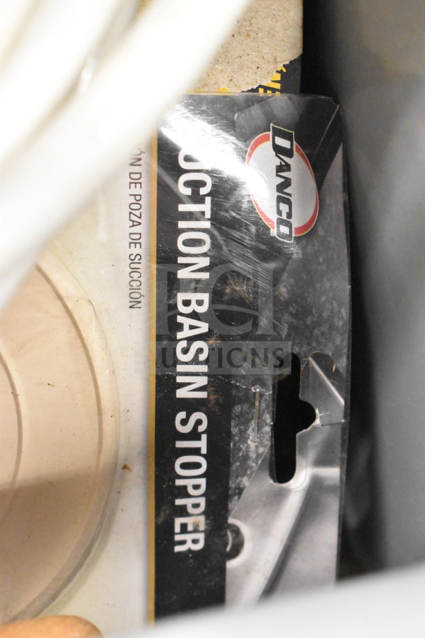 Lot including Danco suction basin stopper in worn packaging. Features visible label and plastic shell. Condition suggests use.