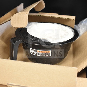 Brand new coffee machine brew basket in box, minor scratches, with warning label for slow removal. Black plastic.