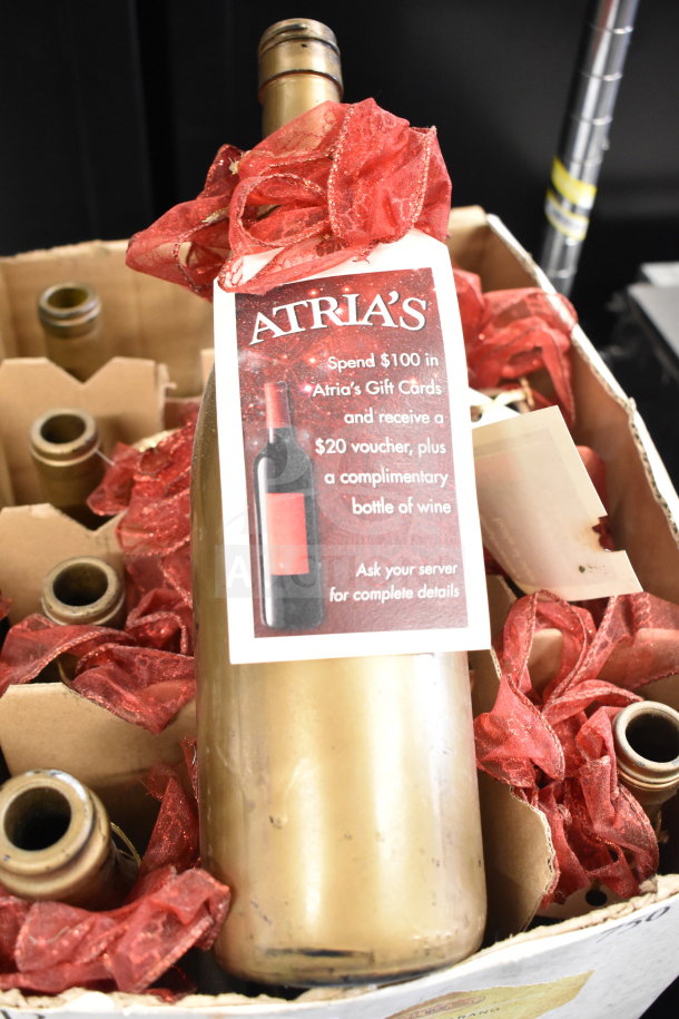 Box of 12 bottles with an Atria's promotion tag, featuring red decorative ribbons and gold-toned bottles.