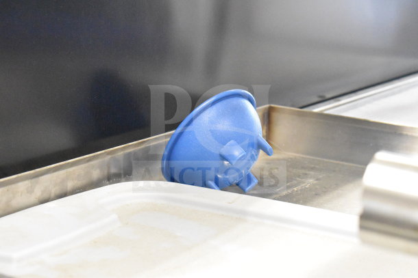 Blue plastic item on metal surface, possibly part of a set of various items including metal panels. Condition appears used.