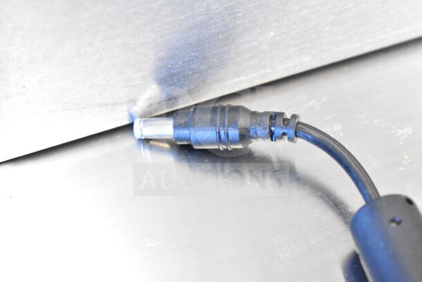 Power cable for TSC TC210 Thermal Transfer Label Printer, black with a connector, shown on a metallic surface.
