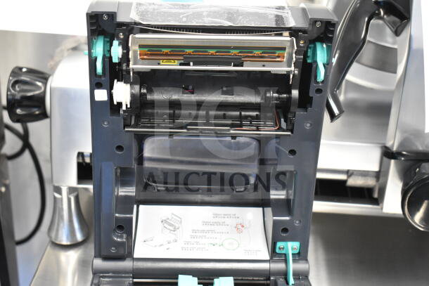 TSC TC210 thermal transfer label printer with open cover, showing internal components and instruction diagram.