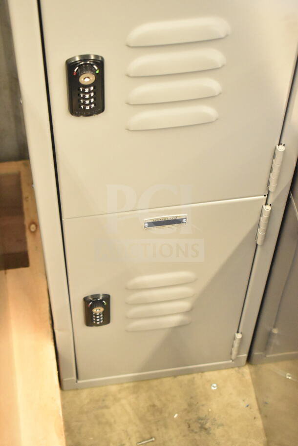 Gray metal locker, four-tier, one wide, 6 ft high, 15 in deep, assembled. Features a combination lock. Brand new, scratch and dent condition. Marked "lockers.com".