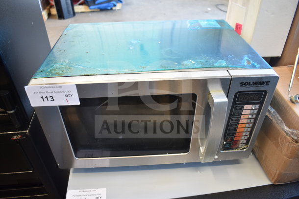 Solwave 180MW1000SS commercial microwave, new with scratches and dents, push button controls, 120V, auction tag visible.