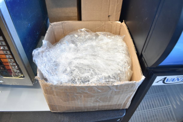 Cardboard box containing wrapped items, including Adcraft Hi Limit, Avantco slicer pusher handle, Carnival King waffle grid, and more.