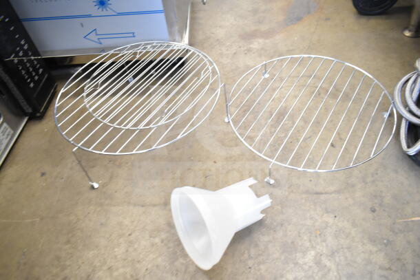Two metal wire racks and a plastic microwave part on a concrete floor; accessories for Wolf MWC24 Microwave Oven.