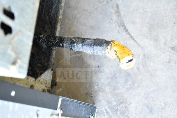 Vulcan commercial gas deep fat fryer pipe connection, showing wear and grease buildup on the floor.