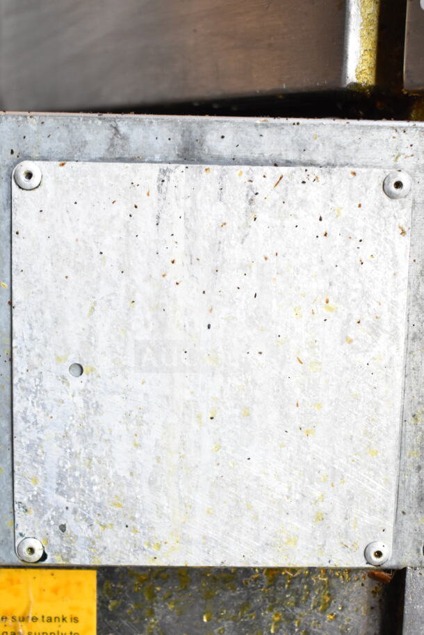 Metal panel of Vulcan gas-powered deep fat fryer, showing signs of use, with visible screws and surrounding area marks.