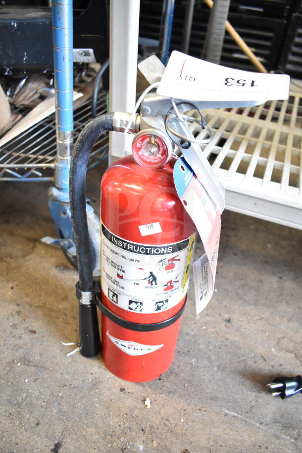 Red Amerex fire extinguisher with attached hose and instruction label. Tags indicate buyer pick-up required, no shipping.