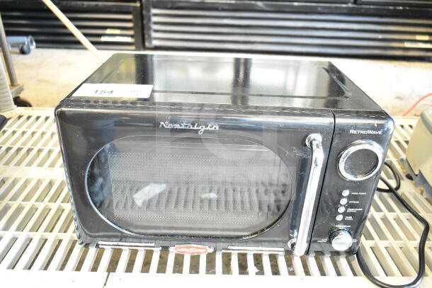 Nostalgia NRMO7BK6A RetroWave countertop microwave, black. 120 volts, 1 phase, features dial controls, good condition.