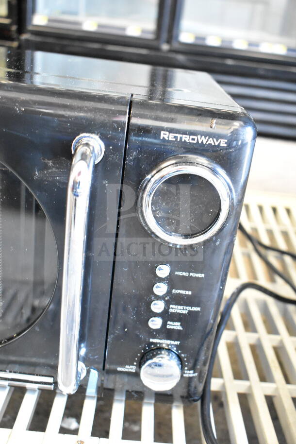 Nostalgia NRMO7BK6A RetroWave countertop microwave, black, features chrome accents, dial controls, visible power settings.