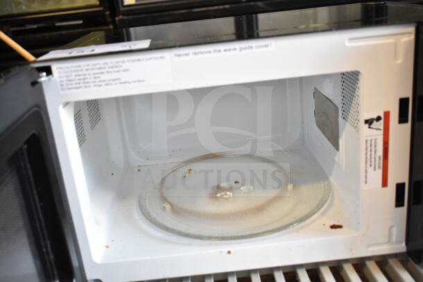 Nostalgia NRMO7BK6A countertop microwave, 120 volts, interior shows signs of use. Safety labels visible.