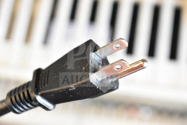 Close-up of a black two-prong plug from a Nostalgia NRMO7BK6A Countertop Microwave, suitable for 120 volts, 1 phase.