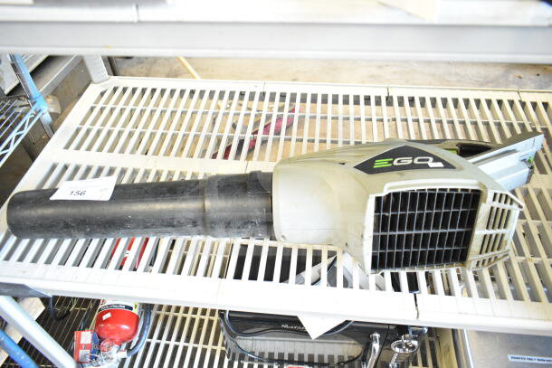 EGo Power+ battery-powered blower, black and gray, used condition, auction label marked "156," on white shelving.