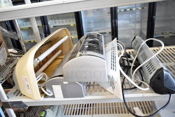 Five various bug zappers, 120 volts, 1 phase, mixed designs and conditions, labeled for auction, on metal shelf.
