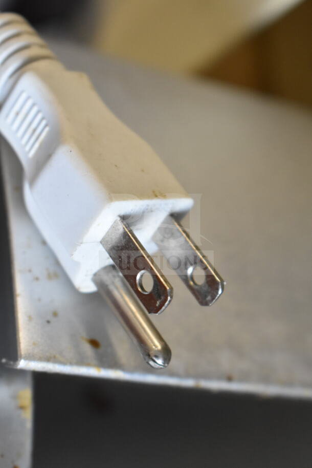 Close-up of a white electrical plug from a 120-volt bug zapper, highlighting the two prongs and cord texture.