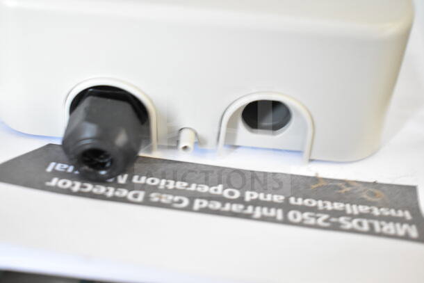 Emerson MRLDS-250 infrared gas detector, white casing, with connector ports. Manual text partially visible.
